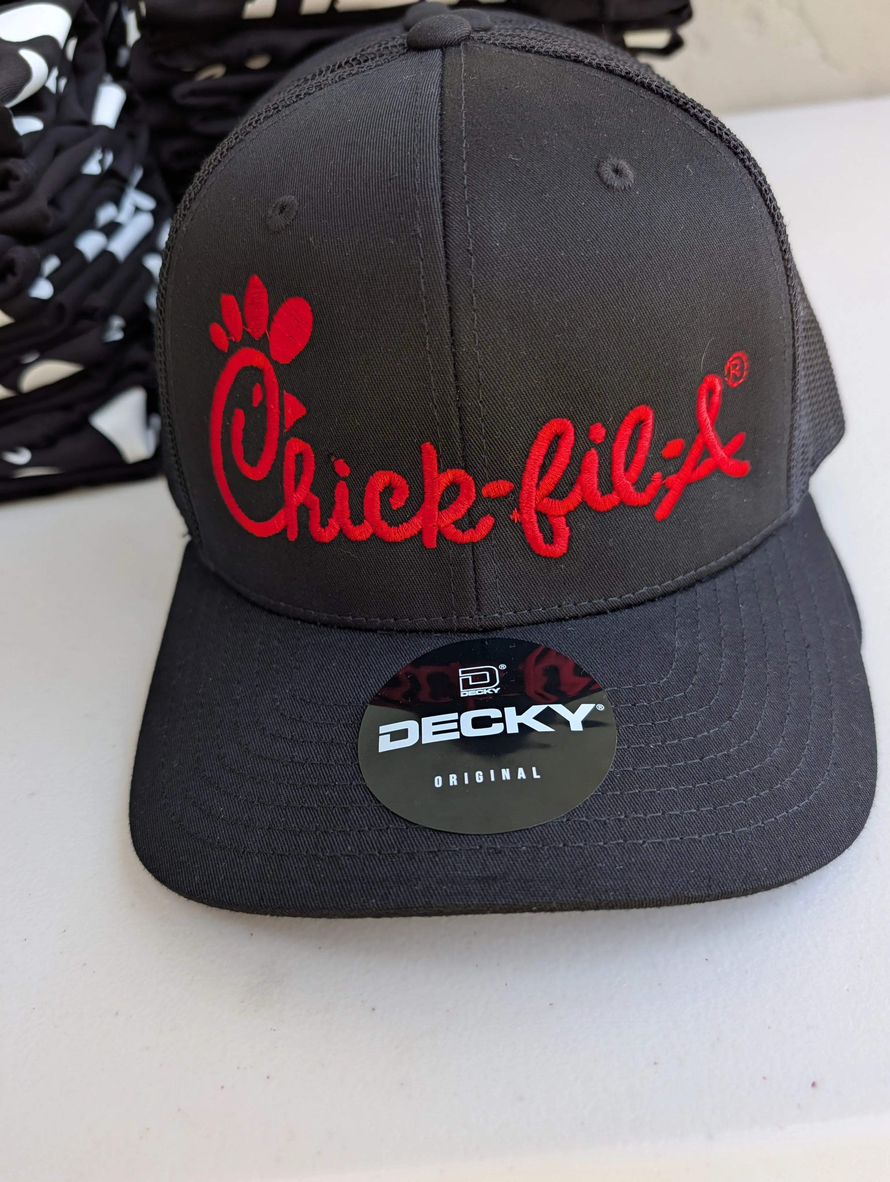 Close-up of red Chick-fil-A script embroidery on a black trucker cap